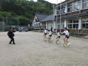校舎をバックに一輪車に乗る児童