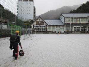 雪の中、校庭を歩く児童