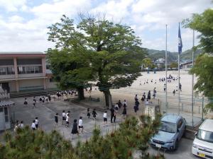 地震の避難訓練で運動場に避難する児童