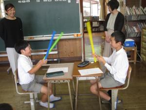 3本の棒をもって遊びを考える児童