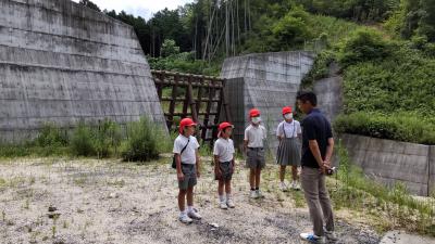 砂防ダムの前で話を聞く児童