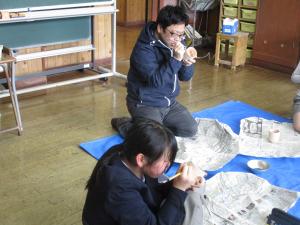 絵付けする児童と先生